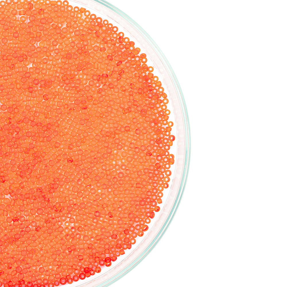Orangefarbener Fischrogen füllt eine Glasschale, von oben betrachtet, mit einem weißen Hintergrund auf der rechten Seite – er erinnert an Mini-Glasperlen, die aufgrund ihrer leuchtenden Farbe und ihres zarten Aussehens häufig in Bastelprojekten oder beim Schmuckbasteln verwendet werden.