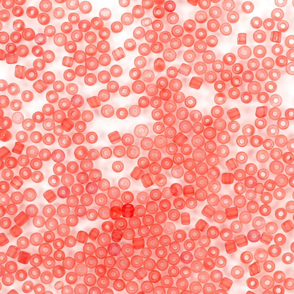 Viele kleine, durchscheinende rote Mini-Glasperlen sind zufällig auf einem weißen Hintergrund verteilt – ideal für Bastelprojekte oder zum Basteln von Schmuck.