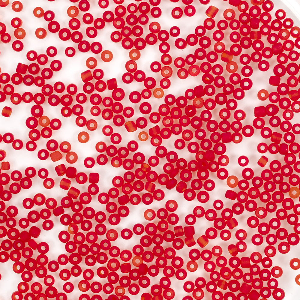 Viele kleine rote, runde Mini-Glasperlen sind zufällig auf einem weißen Hintergrund verteilt – ideal für Schmuck-Bastelprojekte.