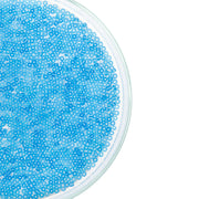 Runde Petrischale, gefüllt mit vielen kleinen blauen Mini-Glasperlen, ideal für Bastelprojekte oder zum Basteln von Schmuck, abgebildet vor weißem Hintergrund.