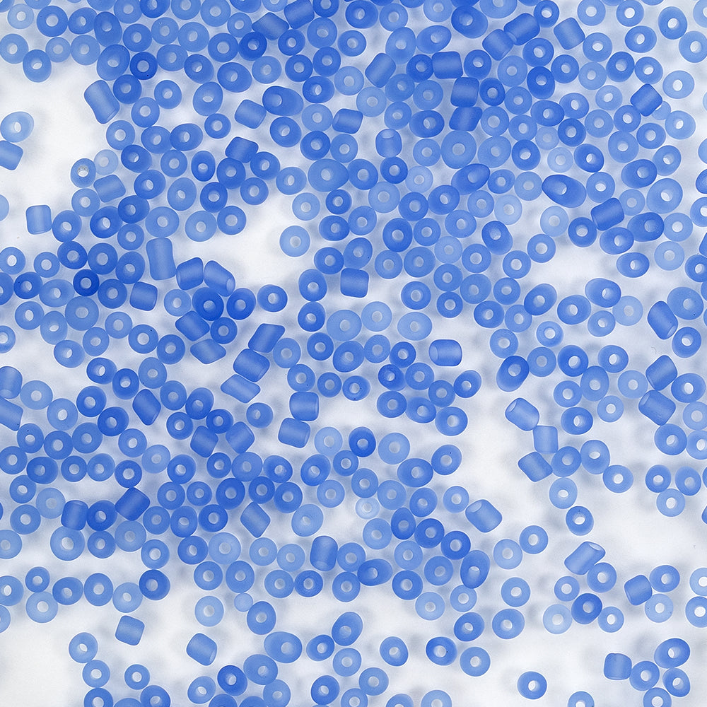 Viele kleine, durchscheinende blaue, zylindrische Perlen, die auf einem weißen Hintergrund verstreut sind.