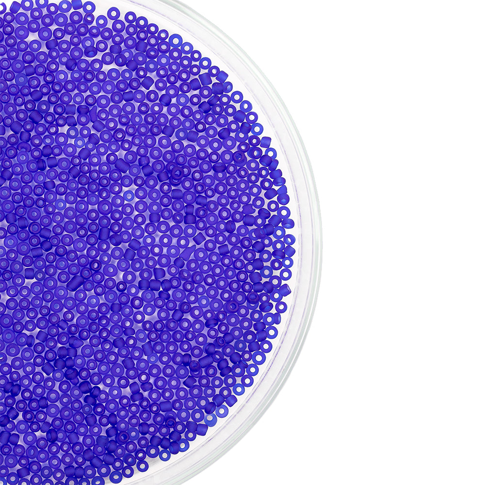 Eine durchsichtige Schale, gefüllt mit vielen kleinen, runden, blauen Mini-Glasperlen – ideal zum Schmuckbasteln oder für andere kreative Bastelprojekte –, abgebildet vor einem weißen Hintergrund.