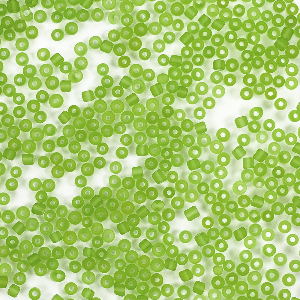 Verstreute grüne Plastikperlen auf einer weißen Fläche, von oben betrachtet – ideal für Bastelprojekte oder als Mini-Glasperlen beim Schmuckbasteln.