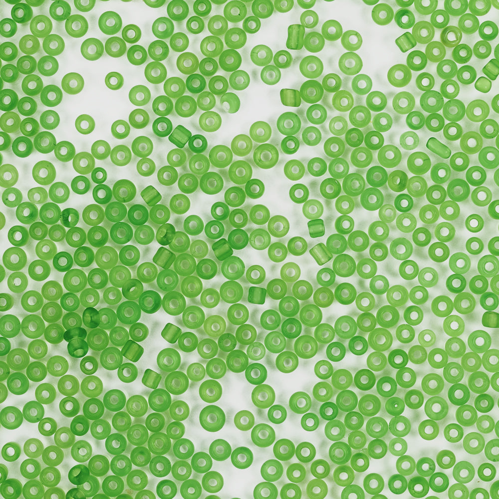 Verstreute, durchscheinende grüne Plastikperlen auf weißem Hintergrund, von oben betrachtet – ideal für Bastelprojekte oder alle, die sich für das Basteln von Schmuck im Mini-Glasperlen-Stil interessieren.