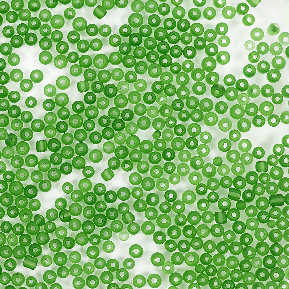 Viele kleine, runde, grüne Bastelperlen sind zufällig auf einem weißen Hintergrund verteilt.