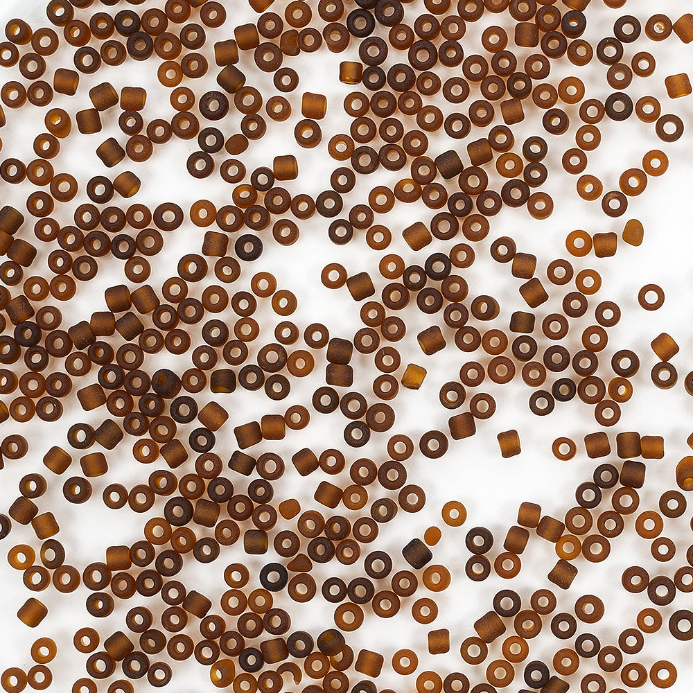 Viele kleine, braune, zylindrische Mini-Glasperlen sind zufällig auf einem weißen Hintergrund verteilt – ideal zum Schmuckbasteln und für kreative Bastelprojekte.