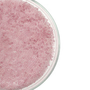 Eine Glasschale, gefüllt mit vielen kleinen, runden, durchscheinenden rosa Mini-Glasperlen auf weißem Hintergrund – ideal für Bastelprojekte oder zum Basteln von Schmuck.