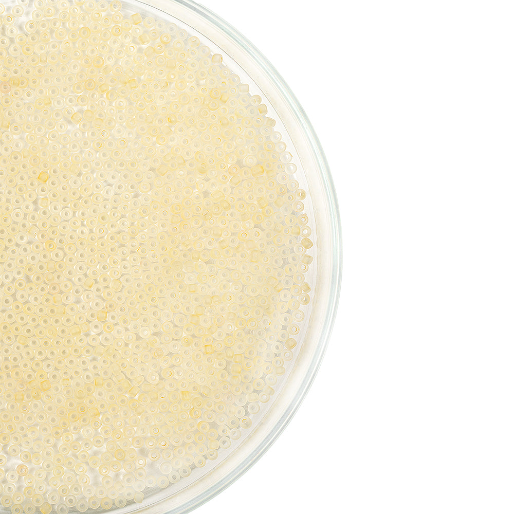 Durchsichtige Schale, gefüllt mit kleinen, runden, hellgelben Mini-Glasperlen, von oben auf weißem Hintergrund abgebildet – ideal zum Schmuckbasteln und für kreative Bastelprojekte.