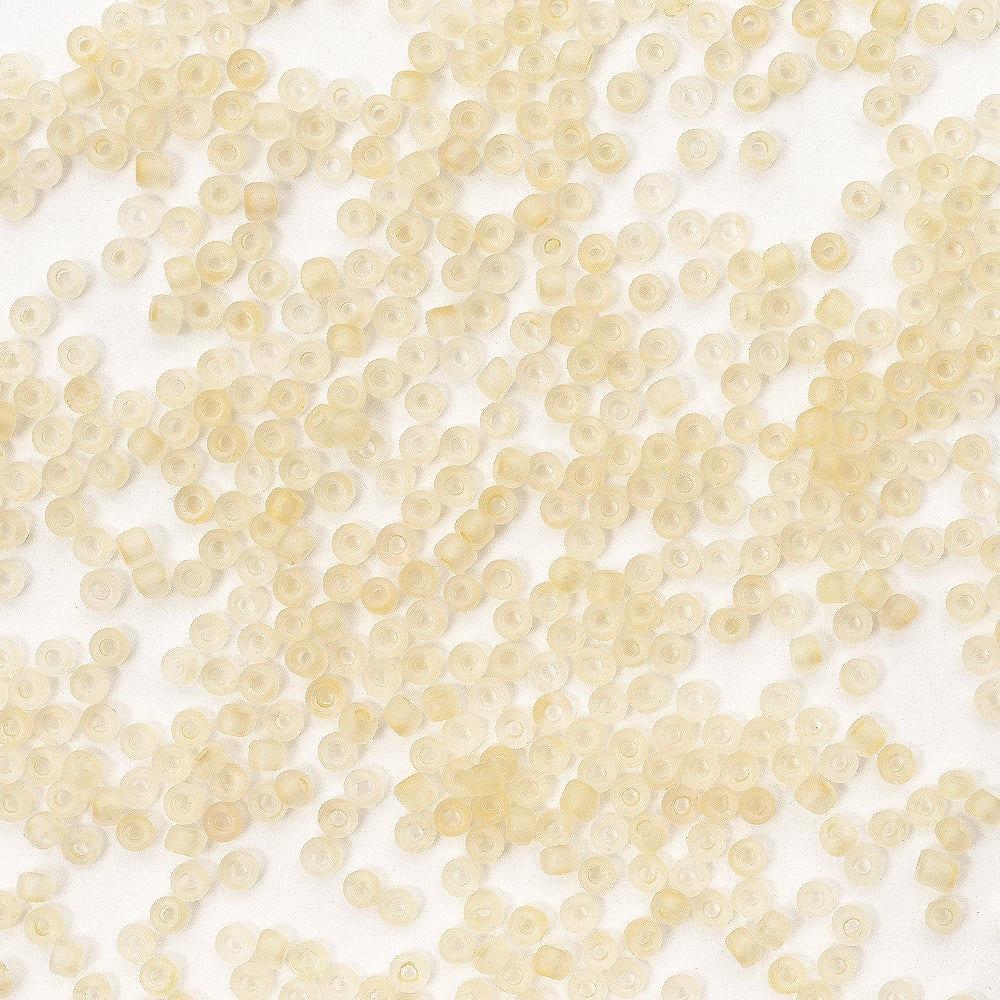 Viele kleine, durchscheinende gelbe Plastikperlen – die wie Mini-Glasperlen aussehen – sind zufällig auf einer weißen Fläche verteilt und eignen sich perfekt für Bastelprojekte oder zum Schmuckbasteln.