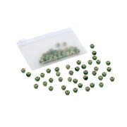 Kleine grüne Perlen, darunter auch handgefertigte Perlen, liegen verstreut neben einem durchsichtigen Reißverschlussbeutel, in dem sich einige Perlen befinden – perfekt für alle, die selbst Schmuck basteln möchten.