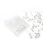 Ein durchsichtiges Täschchen mit kleinen weißen Perlen von Alexandra Renke, ideal für Bastelkreationen oder Scrapbooking, mit ein paar verstreuten Perlen auf weißem Hintergrund.