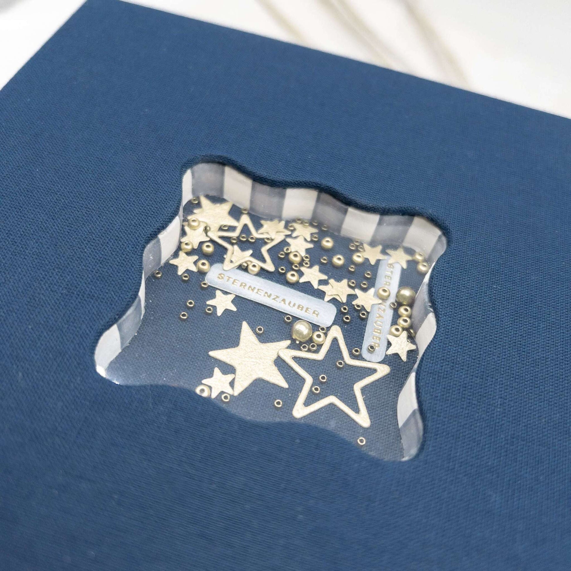 Blaue Schachtel mit wellenförmigem Fenster, hergestellt mit Deep Edge Stanzen von Alexandra Renke, mit goldenen Sternen und Perlen im Inneren.