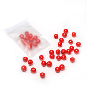 Rote, runde Holzperlen von Alexandra Renke, verstreut auf einer weißen Fläche, einige davon in einer teilweise geöffneten Plastiktüte – ideal für jedes Bastelprojekt.