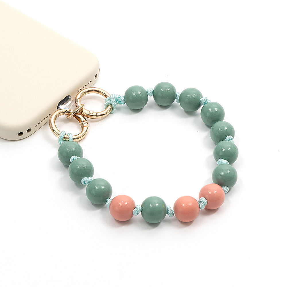 Ein Alexandra-Renke-Handy mit einem Perlenarmband aus grünen und rosa Perlen, goldenen Ringen und bezaubernden Holzperlen – perfekt für ein farbenfrohes Bastelprojekt.