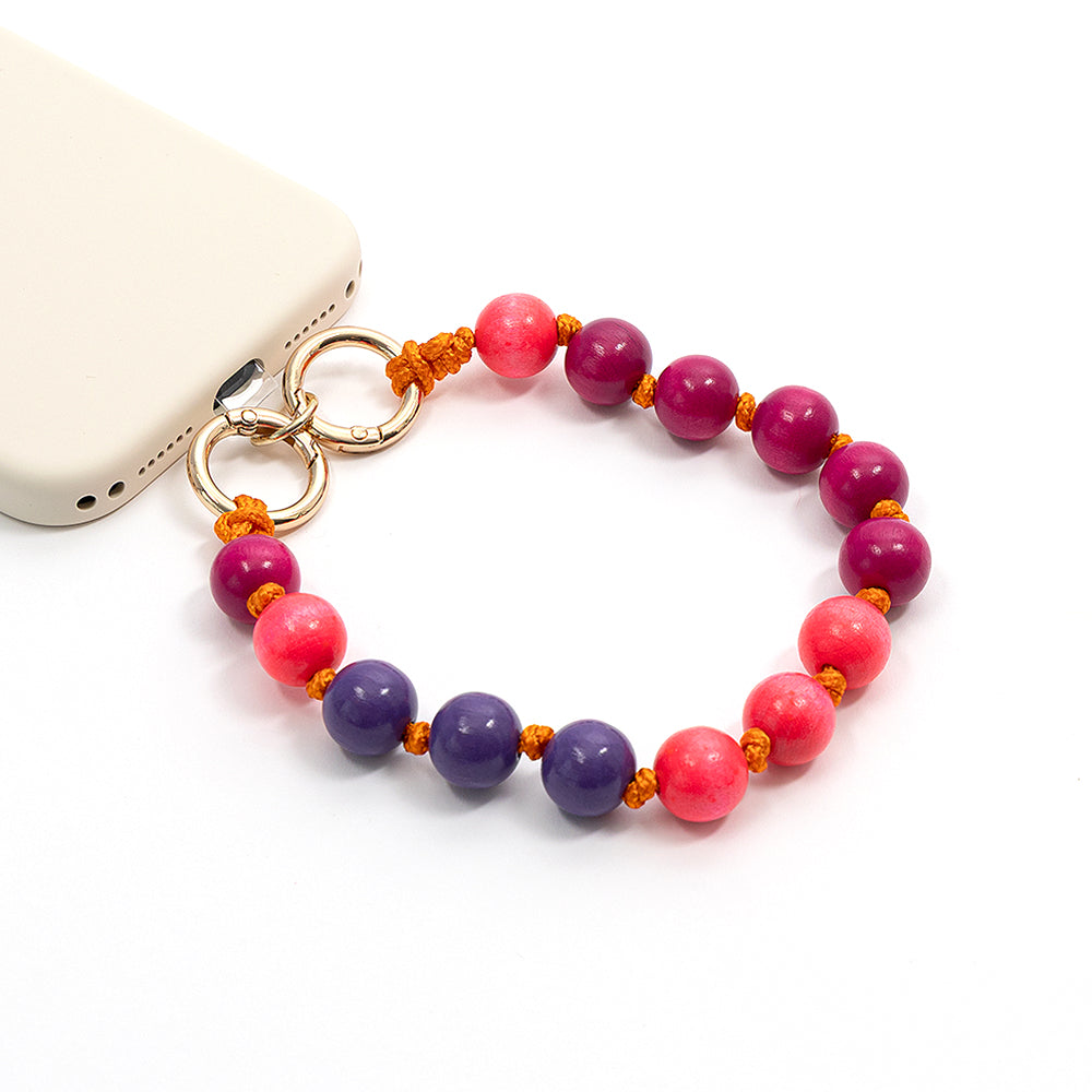 Ein Handy mit einem Schlüsselband zum Umhängen aus rosa und lila Holzperlen, die mit einer orangefarbenen Schnur von Alexandra Renke zusammengebunden sind – ideal als Bastelprojekt für alle, die kreative, handgefertigte Accessoires lieben.