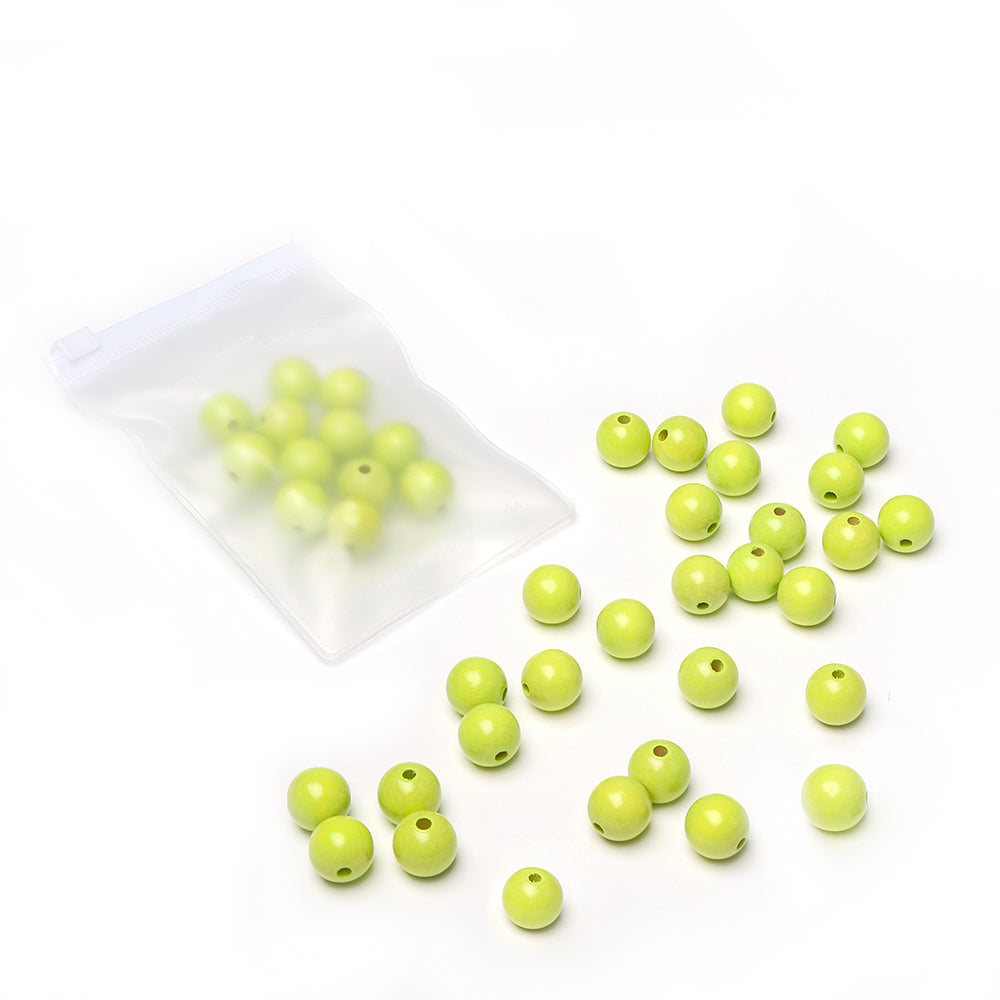 Limettengrüne Holzperlen von Alexandra Renke, verstreut auf einer weißen Unterlage, dazu weitere Perlen in einem kleinen, durchsichtigen Beutel mit Reißverschluss – perfekt für dein nächstes Bastelprojekt.