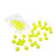 Gelbe, runde Holzperlen von Alexandra Renke, teils verstreut, teils in einem durchsichtigen, wiederverschließbaren Plastikbeutel, vor weißem Hintergrund – perfekt für DIY-Schmuckprojekte mit nachhaltig produziertem Holz.