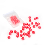 Rosa runde Perlen von Alexandra Renke sind auf einer weißen Fläche verstreut, dazu gibt es noch weitere Holzperlen in einem halbtransparenten Plastikbeutel – perfekt für dein nächstes Bastelprojekt.