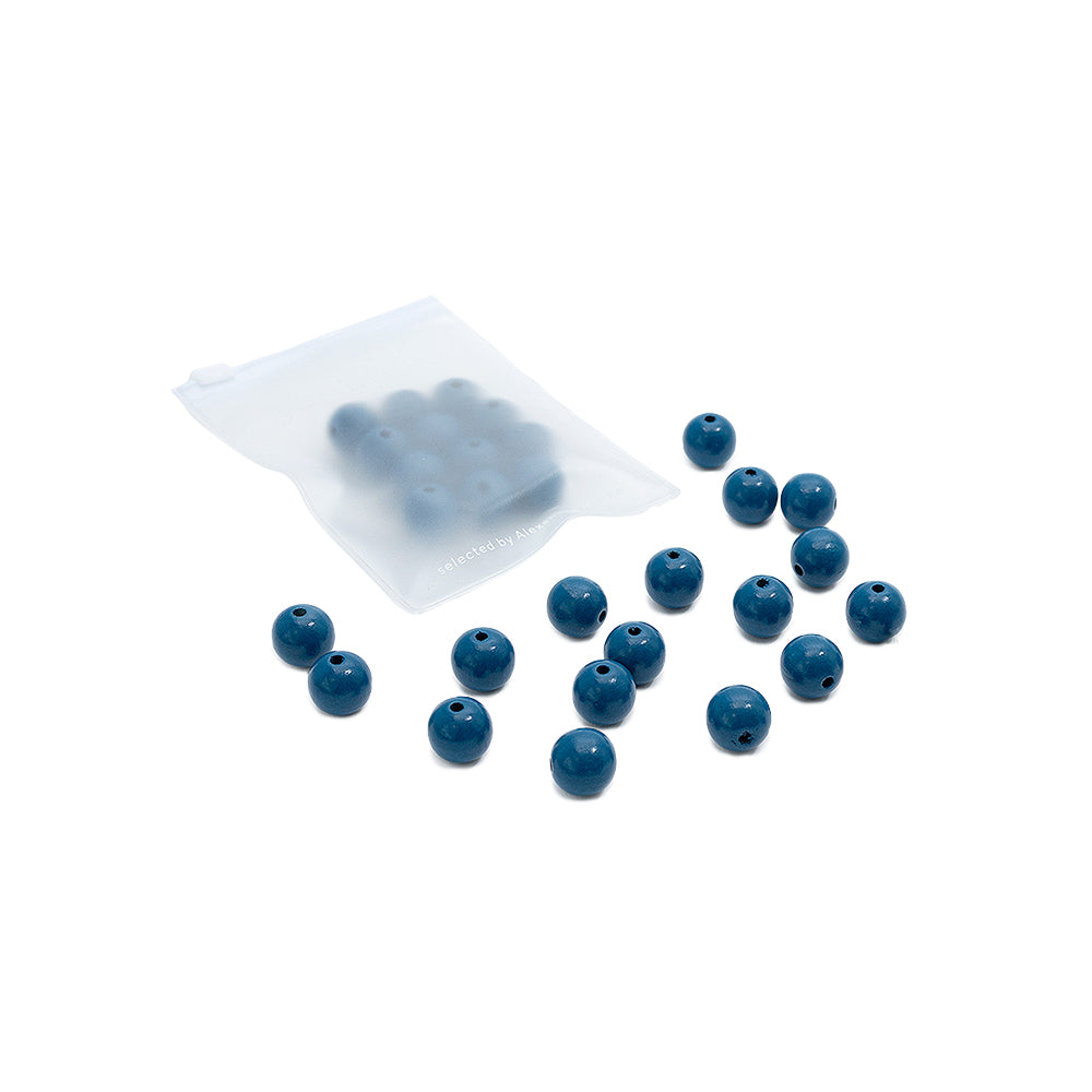 Ein kleines Tütchen von Alexandra Renke mit blauen, runden Holzperlen darin und einigen weiteren blauen Perlen, die außerhalb des Tütchens verstreut sind – perfekt für dein nächstes Bastelprojekt.