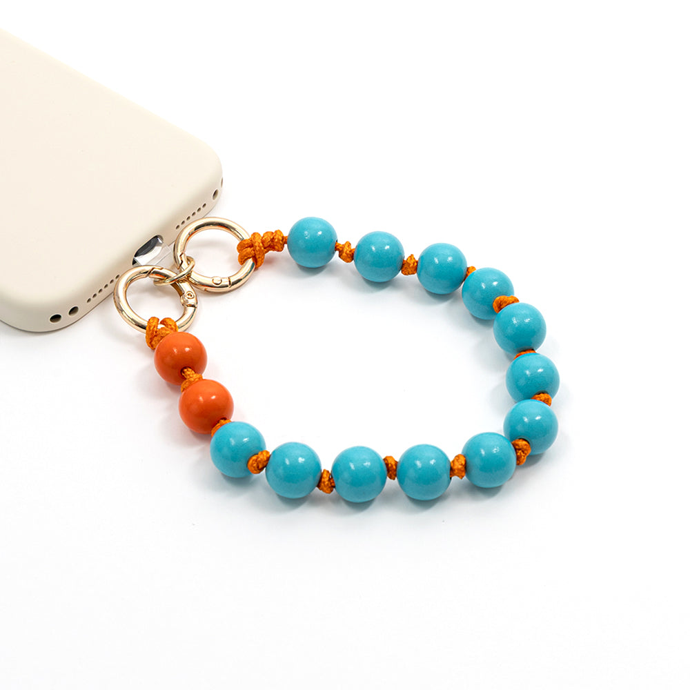 Eine Handyhülle von Alexandra Renke mit einem Perlenband aus blauen und orangefarbenen Perlen an einer orangefarbenen Kordel, ergänzt durch bezaubernde Holzperlen, die für einen Hauch von DIY-Schmuck-Flair sorgen.