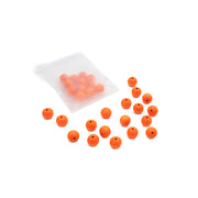 Ein mattes Säckchen mit orangefarbenen Holzperlen von Alexandra Renke, von denen sich einige im Inneren befinden und andere auf einer weißen Fläche verstreut sind – perfekt als Inspiration für dein nächstes Bastelprojekt oder um selbst Schmuck herzustellen.