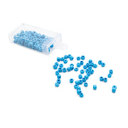 Kleine blaue Rocailles-Perlen von Alexandra Renke ergossen sich aus einem durchsichtigen Plastikbehälter auf eine weiße Fläche und verliehen ihr den Charme einer Vintage-Optik.