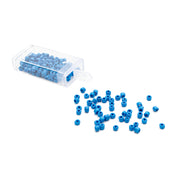 Kleine blaue Rocailles-Perlen von Alexandra Renke im Vintage-Stil rieseln aus einem durchsichtigen Plastikbehälter auf eine weiße Fläche.