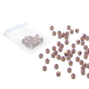 Eine durchsichtige Tasche und verstreute Alexandra Renke handgefertigte Holzperlen mit einem violetten Boden, goldenen gepunkteten grafischen Mustern, und einem großen Öhr auf weißem Hintergrund.