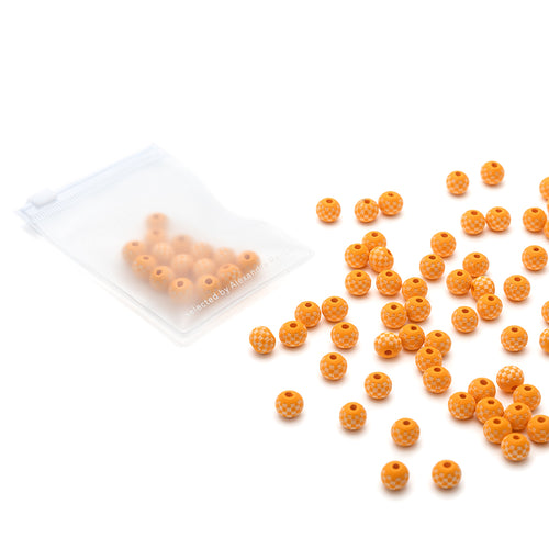 Ein Set kleiner, runder, orangefarbener Holzperlen von Alexandra Renke, einige lose und andere in einem durchsichtigen Beutel mit Reißverschluss - ideal für handgefertigte Bastelzubehörprojekte.