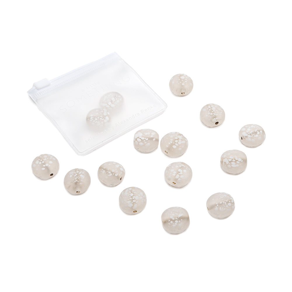 Runde, beige Glasperlen mit Craquelé-Muster von Alexandra Renke – ideal für Schmuck-Bastelprojekte oder Buchbindeprojekte – liegen verstreut auf weißem Hintergrund neben einem kleinen, durchsichtigen Beutel mit Reißverschluss.