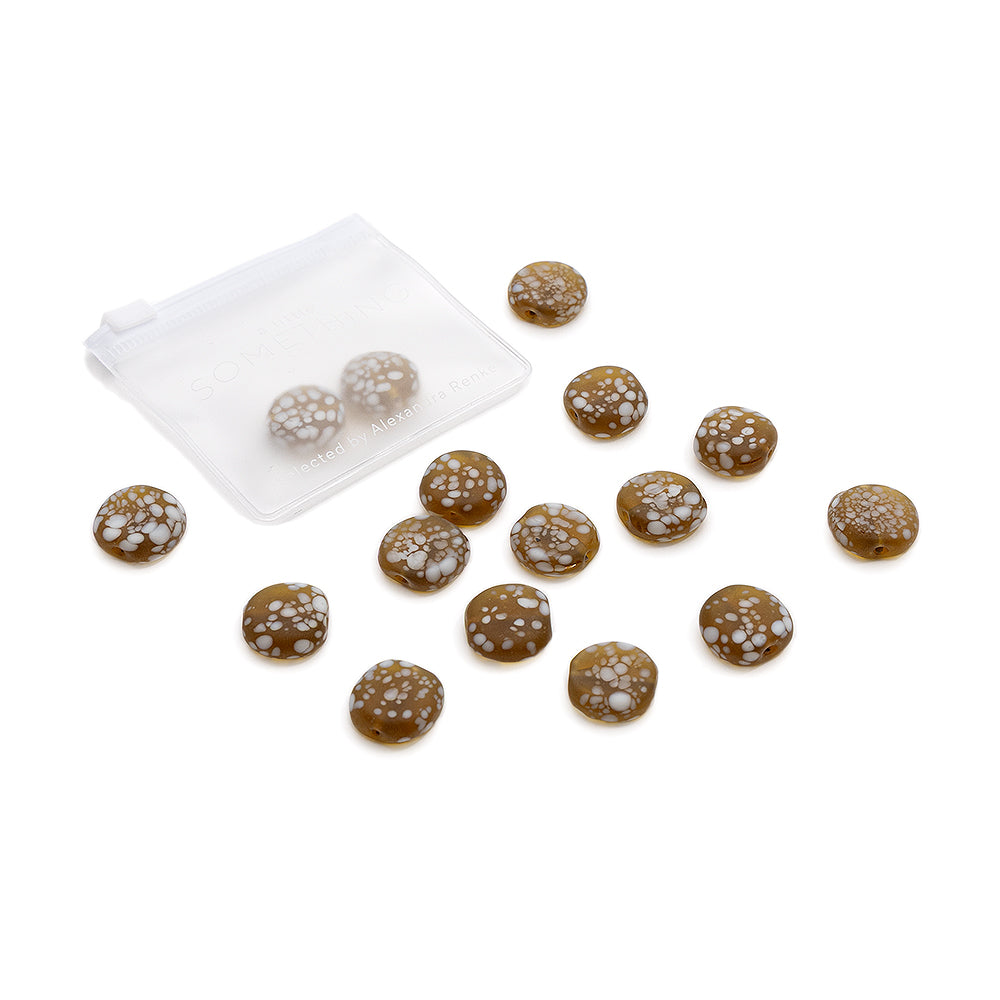 Ein kleines, durchsichtiges Säckchen enthält braune, runde Bonbons mit weißen Flecken – sie sehen aus wie matte Glasperlen und eignen sich perfekt für DIY-Projekte von Alexandra Renke.