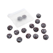 Vierzehn matte, glasperlenähnliche dunkle Bonbons mit weißen Sprenkeln, von denen einige in einem mattierten, wiederverschließbaren Beutel von Alexandra Renke verpackt sind. Ideal für kreative Bastelprojekte oder als einzigartige dekorative Note.
