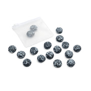 Vierzehn schwarze Steine mit weißen Sprenkeln liegen neben einem kleinen, durchscheinenden Säckchen, zusammen mit einem Set runder Glasperlen von Alexandra Renke für Ihr nächstes DIY-Schmuckprojekt.