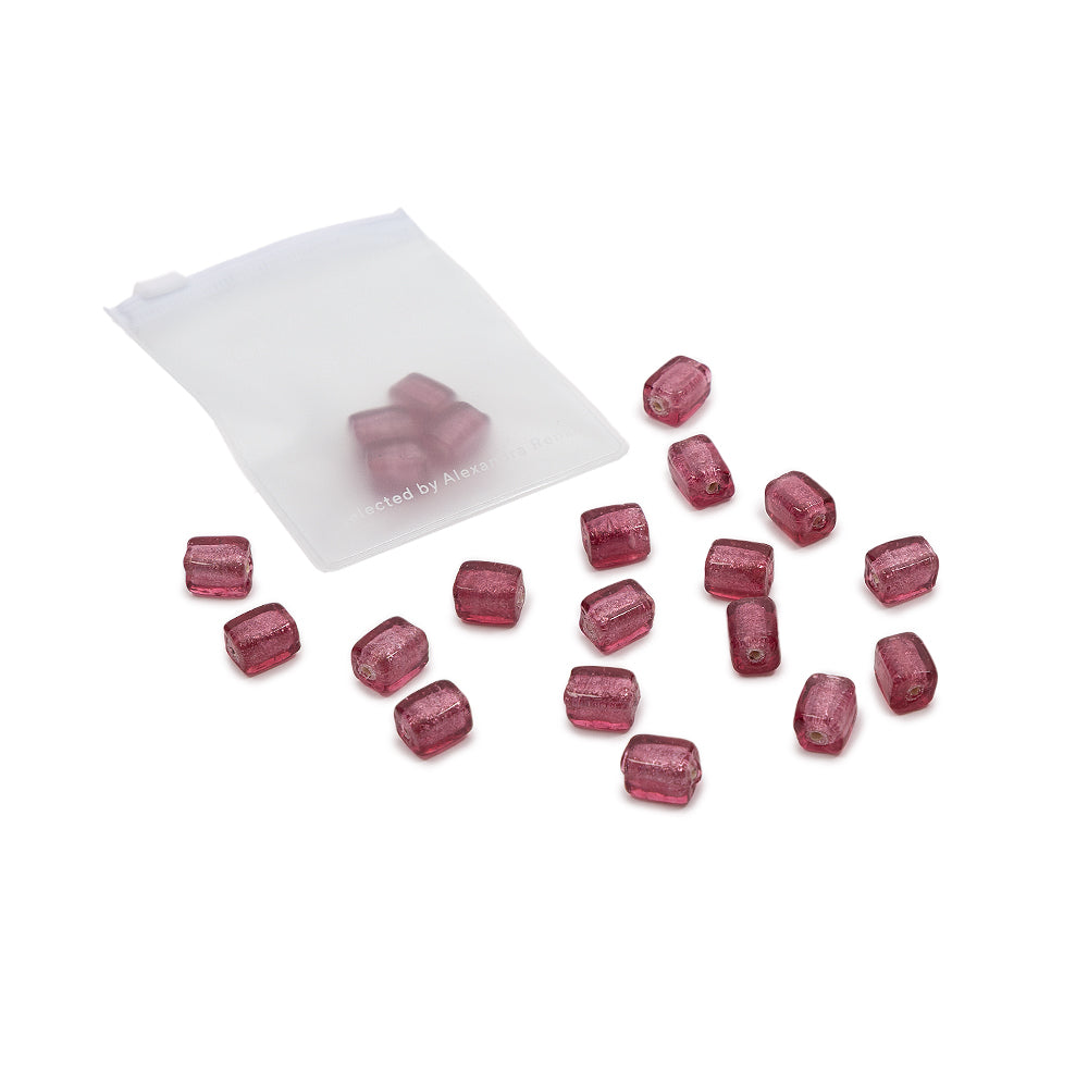 Ein kleines, mattiertes Säckchen, auf dessen weißem Hintergrund mehrere durchscheinende, violette Glasperlen verstreut sind – perfekt für DIY-Projekte und kreative Ideen.