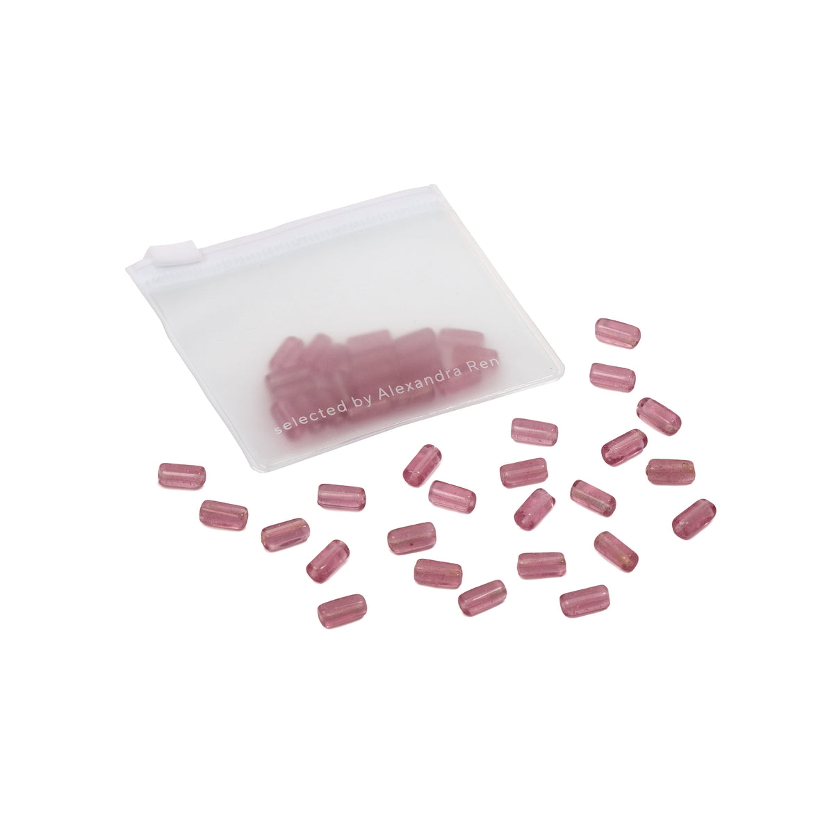 Durchsichtiger Beutel mit rosa, kapselartigen Tabletten, die auf weißem Hintergrund verstreut sind – die perfekte Inspiration für DIY-Projekte oder um Handarbeitskreationen einen Farbtupfer zu verleihen.