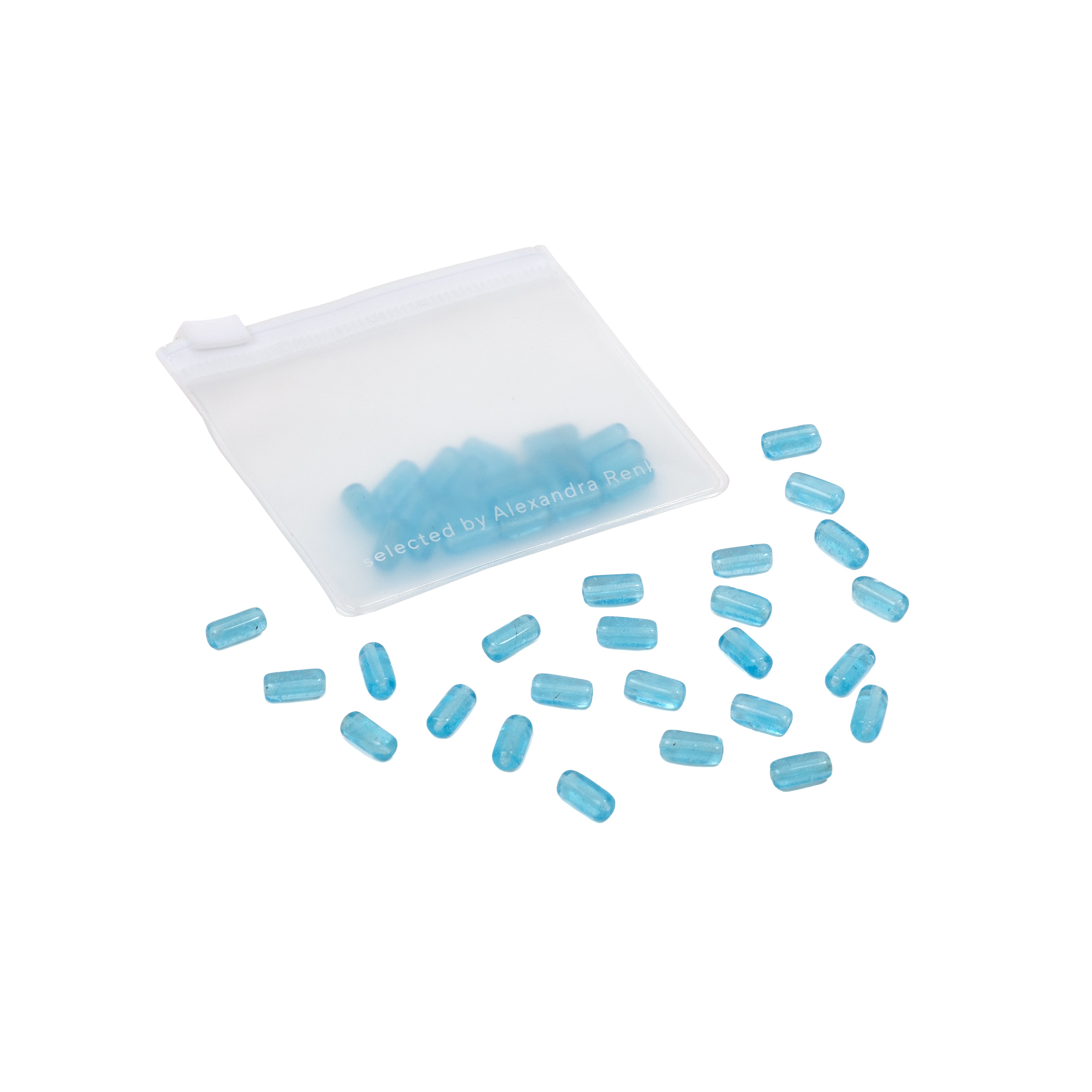 Kleine blaue Pillen, die auf weißem Hintergrund in der Nähe eines durchscheinenden weißen Reißverschlussbeutels verstreut liegen, erinnern an die sorgfältige Präzision, die man bei Handarbeit und DIY-Projekten findet, wobei die glänzende Oberfläche jeder Pille an zarte Glasperlen erinnert.