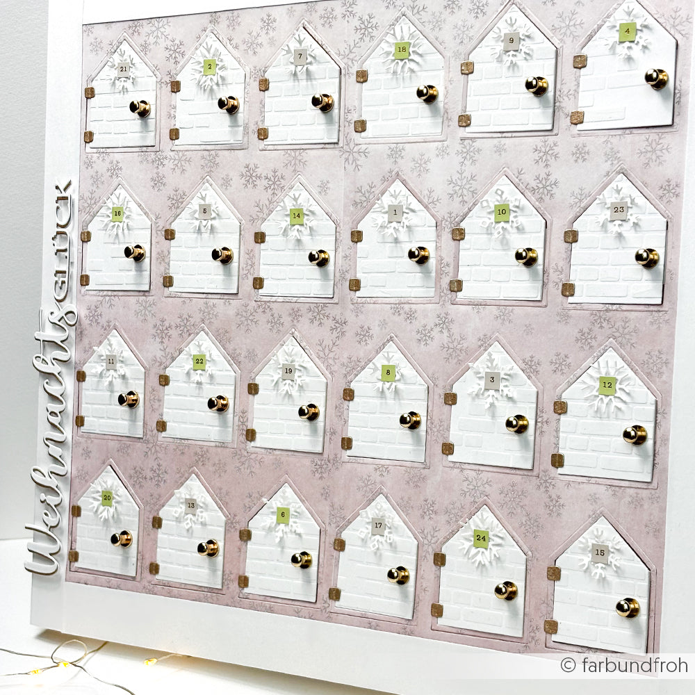 Der pastellrosa-weiße PAPPcut Haus Adventskalender von Alexandra Renke zeigt 24 nummerierte Türchen in Form von Häusern mit goldenen Knöpfen, die mit der Buchbindetechnik hergestellt wurden und so für zusätzlichen Charme sorgen.