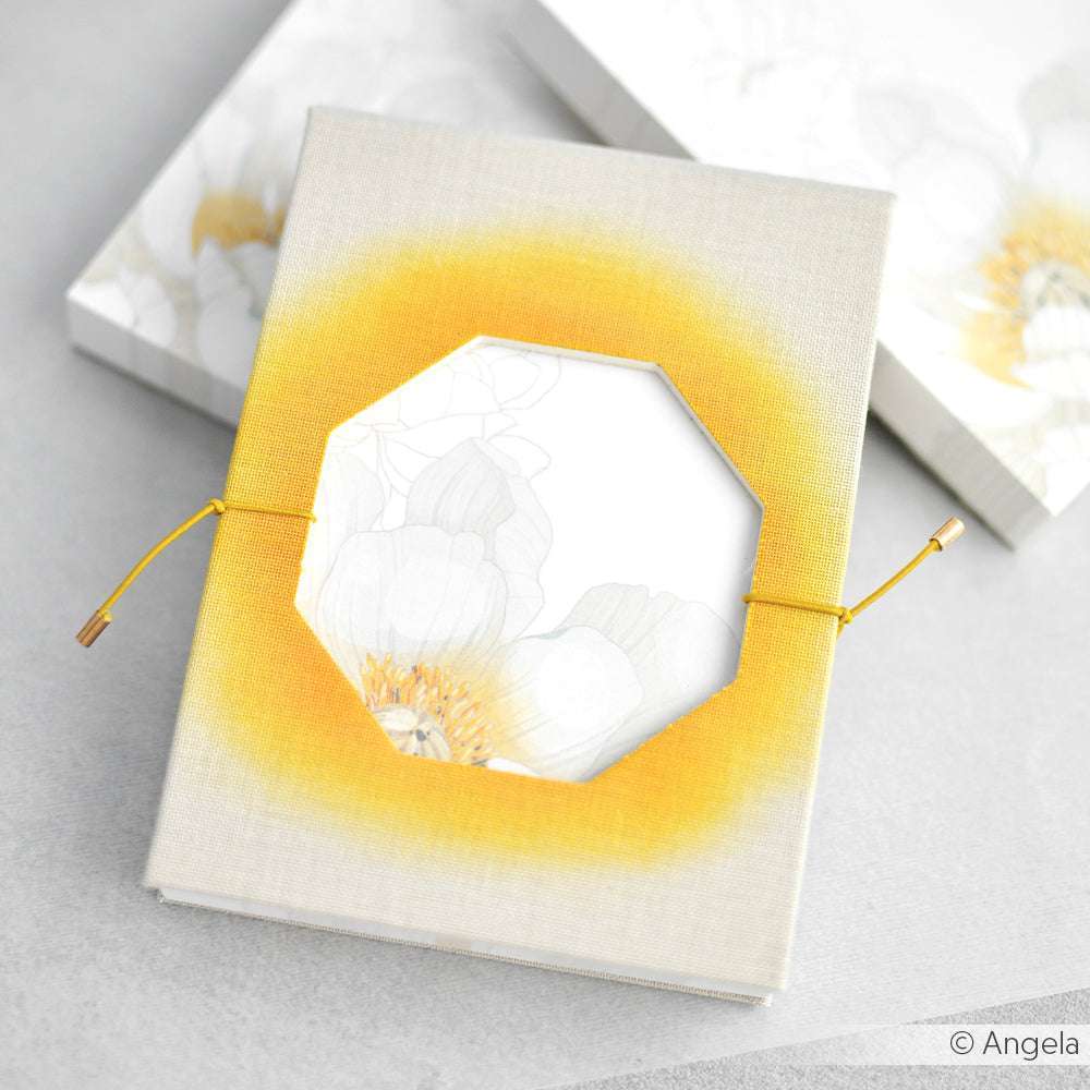 Ein beigefarbenes Buch von Alexandra Renke mit einem gelben Achteckausschnitt und einer gelben Schnur, die mit PAPPcut-Präzision gefertigt wurde, ruht auf einer hellen Oberfläche - eine elegante Anspielung auf moderne Buchbindetechniken.