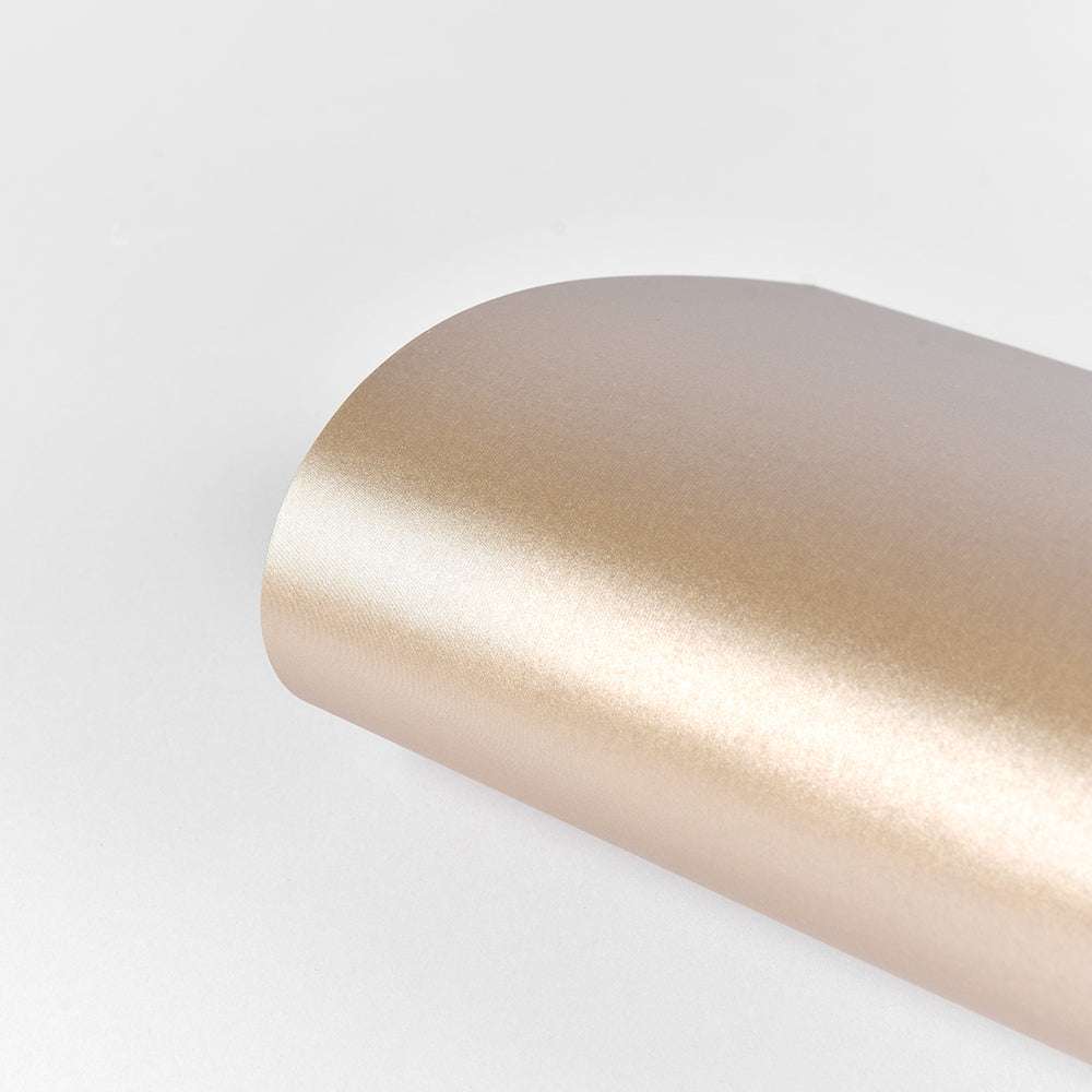 Ein gerolltes Blatt ☆ 310 g/m² Schimmer-Effekt Papier in Goldmetallic ist auf einem schlichten weißen Hintergrund abgebildet - ideal für elegante Papierkunstprojekte.