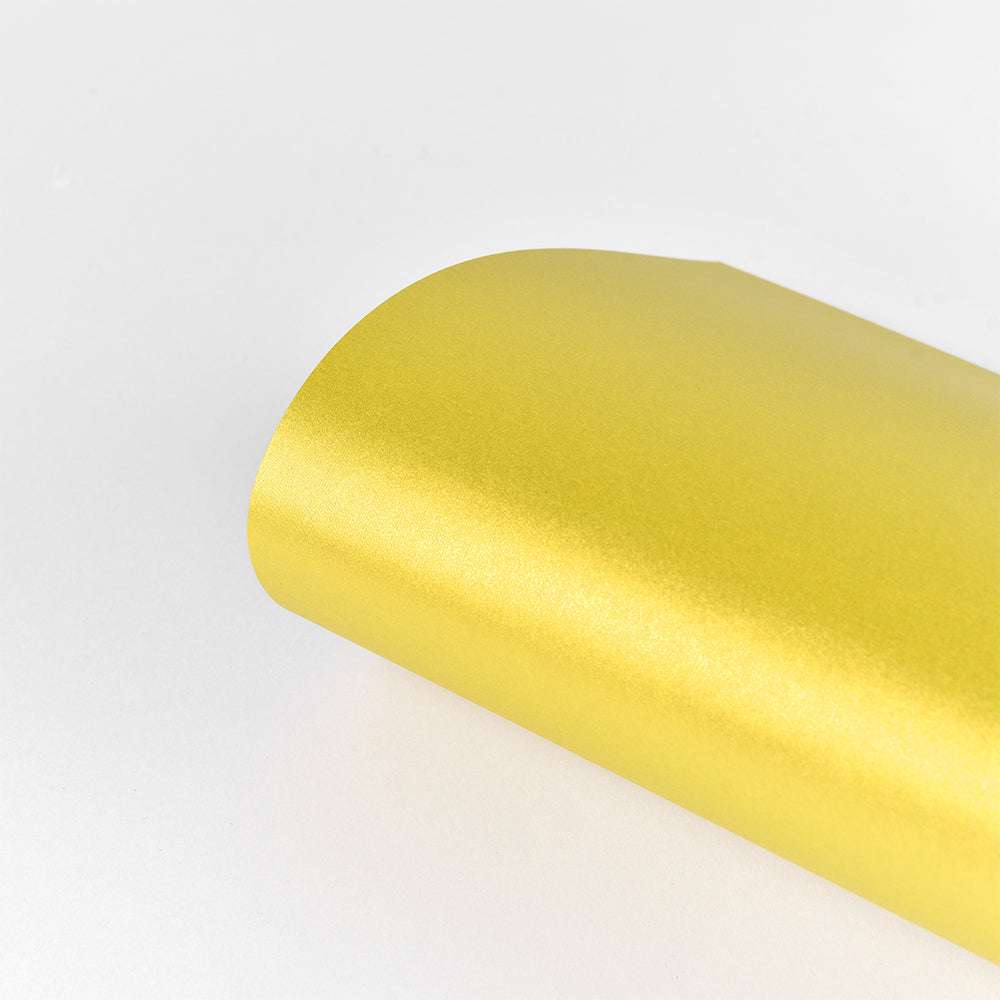 Ein gerolltes Blatt goldmetallisch glänzendes Schimmer-Effekt Papier (310 g/m²) von ☆ auf einem schlichten weißen Hintergrund, ideal für Papierkunst und luxuriöse Projekte.