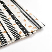 Stapel von ☆ gemusterten Nepalpapieren mit schwarzen Streifen und braunen Blättern auf weiß, ideal für Buchbinden oder Geschenke Verpacken, schräg gestellt.