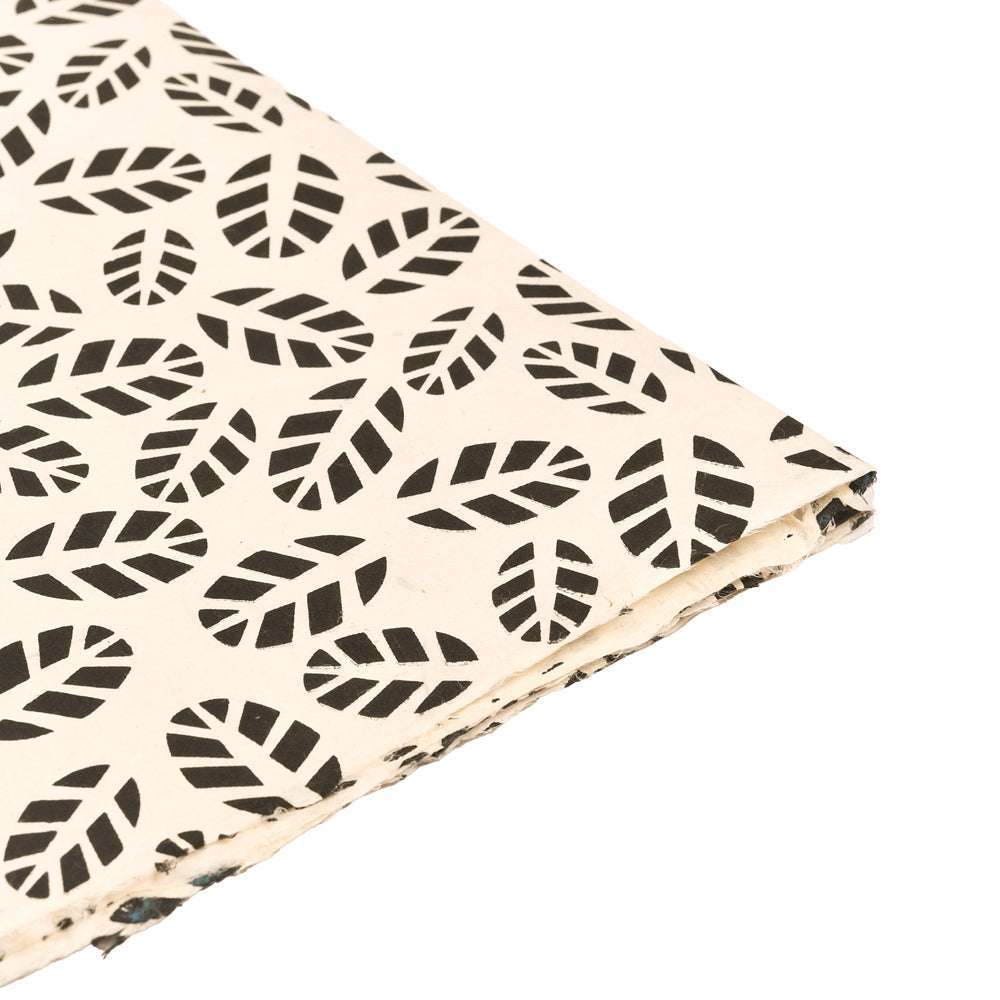 Ein ☆ weißes Nepalpapier mit schwarzem Blattmuster, ideal für Buchbinden oder Geschenke Verpacken, ist gewinkelt auf weißem Hintergrund abgebildet.