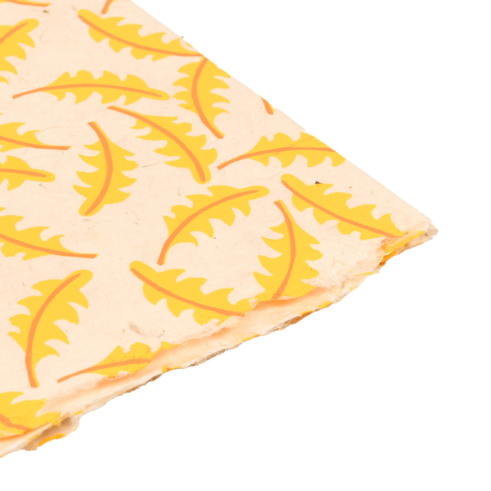 Ein ☆ Nepalpapier-Blatt mit Löwenzahn-Blattmuster in Gelb auf Beige, mit leicht abgenutzten Kanten.