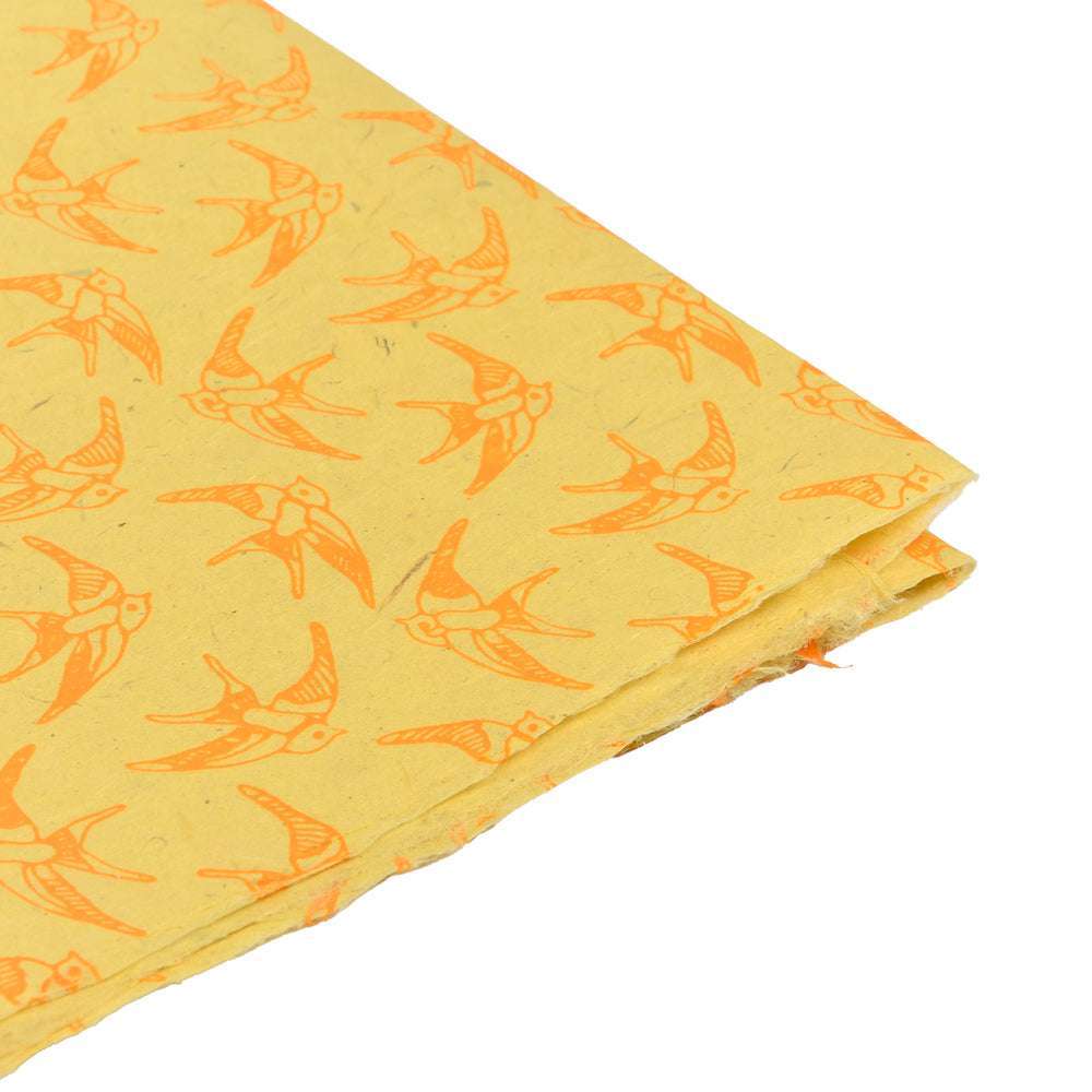 Gelber Stoff mit orangefarbenem Vogelmuster von ☆, an der Ecke ordentlich gefaltet - perfekt für Geschenkverpackungen oder um Buchbindungsprojekten ein einzigartiges Flair zu verleihen.