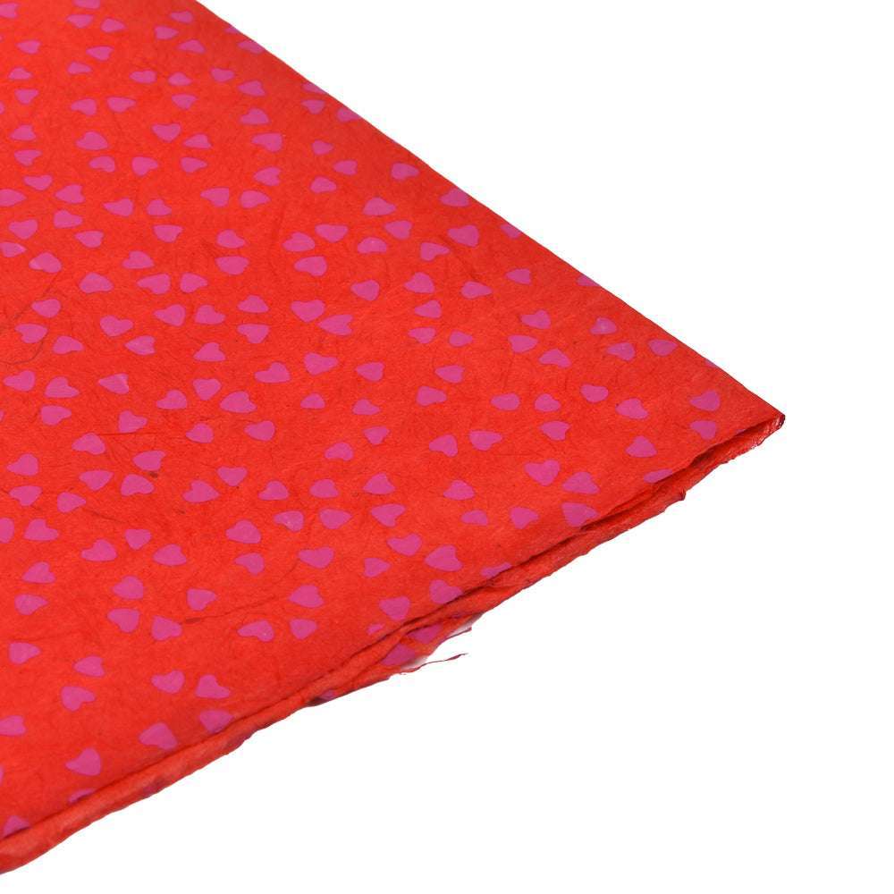 Nepalpapier mit kleinen rosafarbenen Herzmustern, schräg auf weißem Hintergrund - ideal zum Geschenke Verpacken oder Buchbinden.