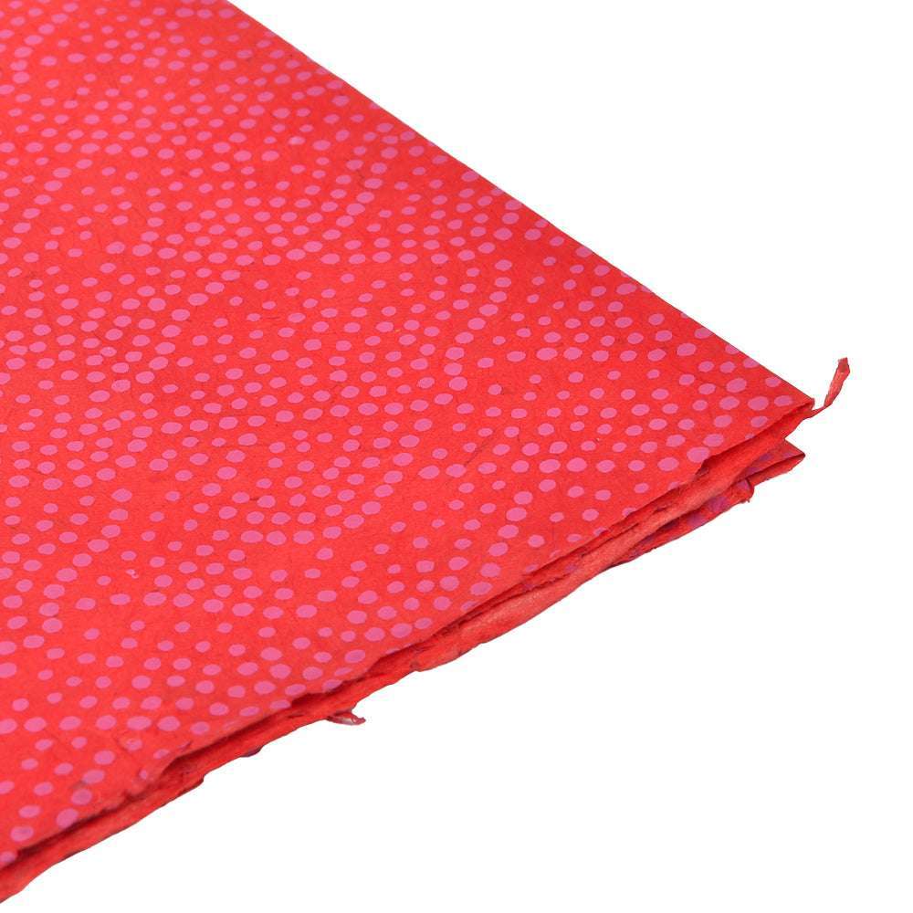 Nepalpapier in Rot mit kleinen, gleichmäßig verteilten rosa Punkten - perfekt zum Buchbinden oder Verpacken von Geschenken. Abgebildet schräg auf weißem Hintergrund.