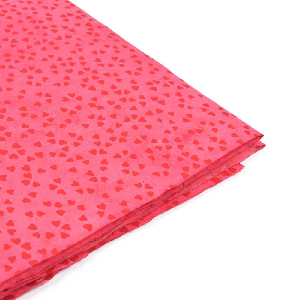Rotes Nepalpapier mit kleinen Herzmustern, ideal zum Verpacken von Geschenken oder zum Buchbinden, gestapelt auf weißem Hintergrund, von oben gesehen.