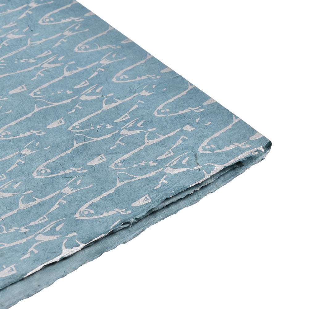 ☆ handgefertigtes blaues Nepalpapier mit einem sich wiederholenden weißen Fischmuster Blau, das schräg auf einem weißen Hintergrund angebracht ist.