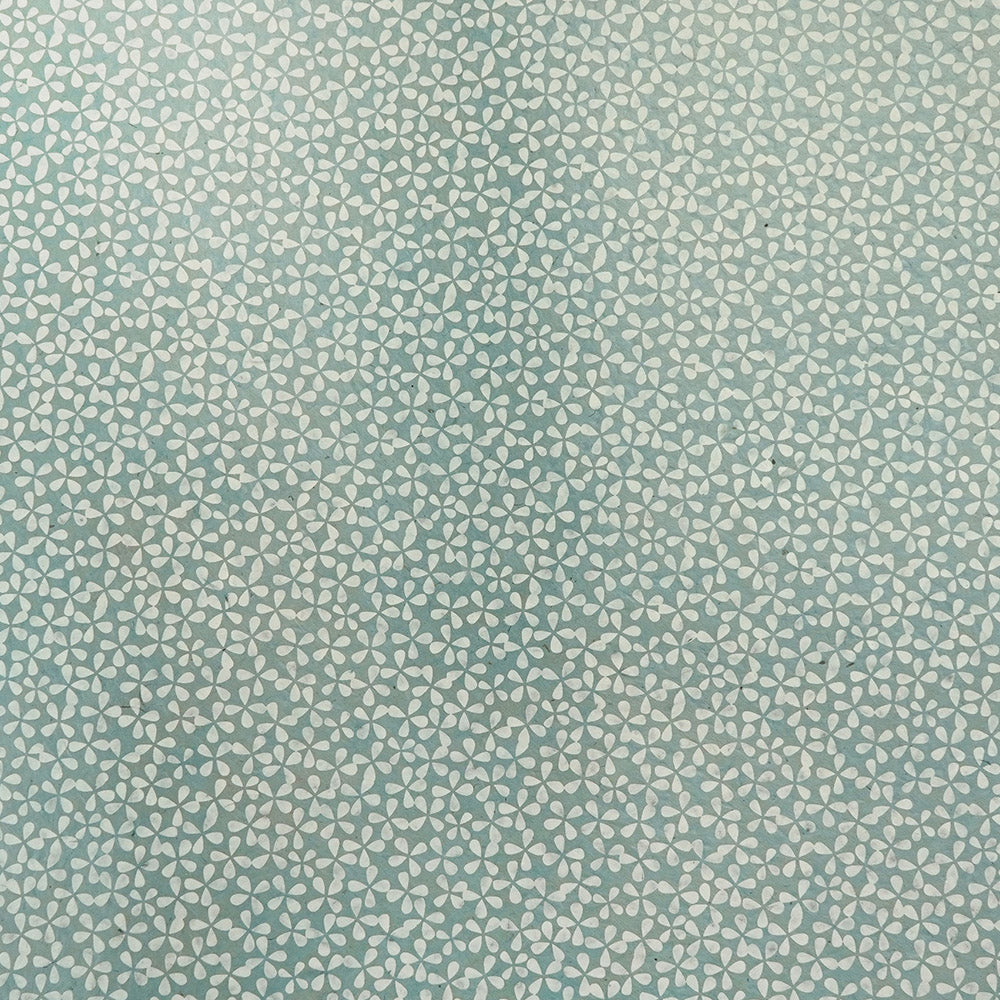 Das Geschenkpapier von ☆’s nachhaltiges Geschenkpapier besticht durch einen hellblauen Hintergrund mit kleinen weißen, abstrakten Blumenmotiven und wird aus einzigartigem, handgeschöpftem Nepalpapier hergestellt – für ein umweltfreundliches Geschenkverpackungserlebnis.