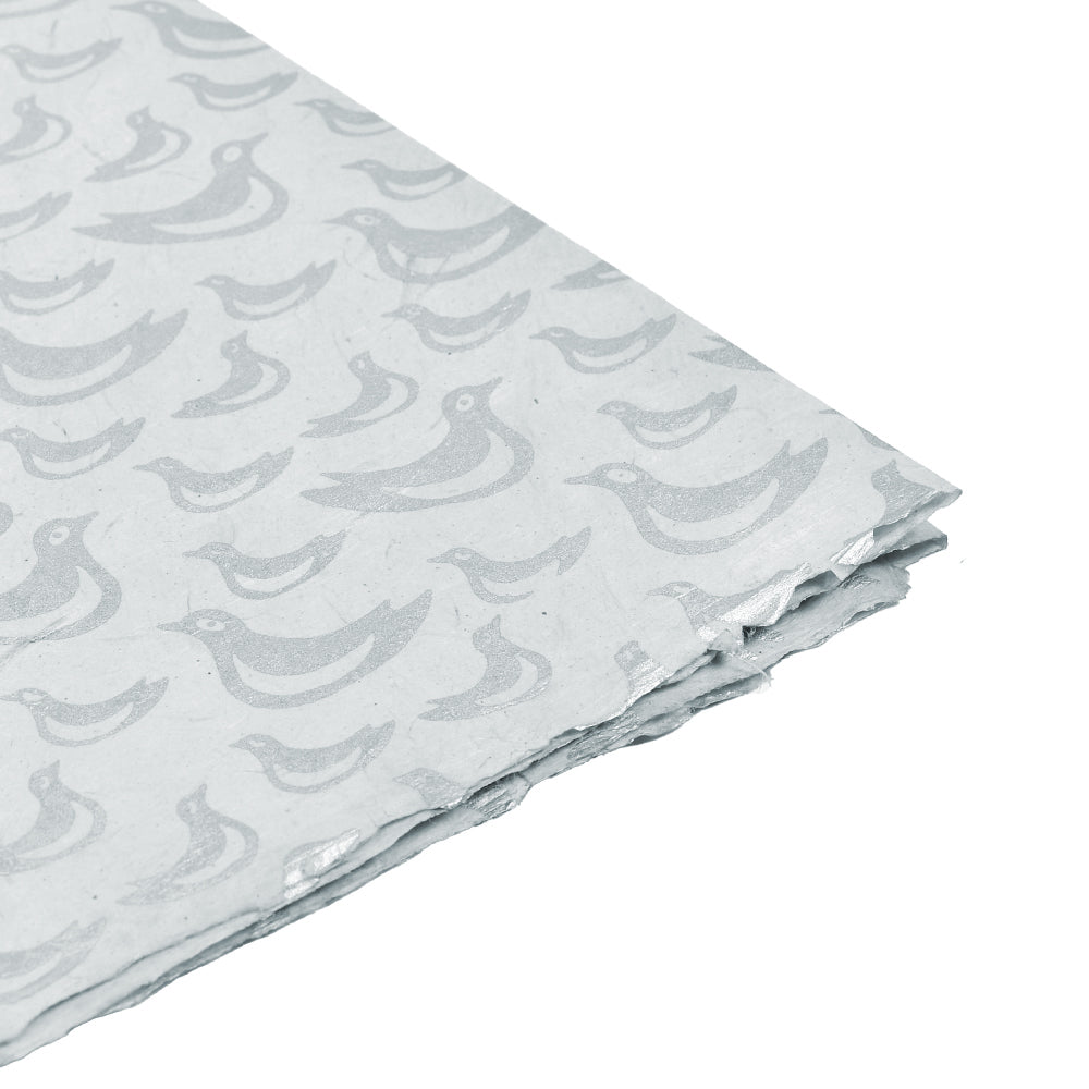 Das weiße Nepalpapier zeigt ein sich wiederholendes Muster aus hellgrauen Vögeln, gefaltet und gestapelt auf weißem Hintergrund - ideal für Geschenke Verpacken oder Buchbinden.